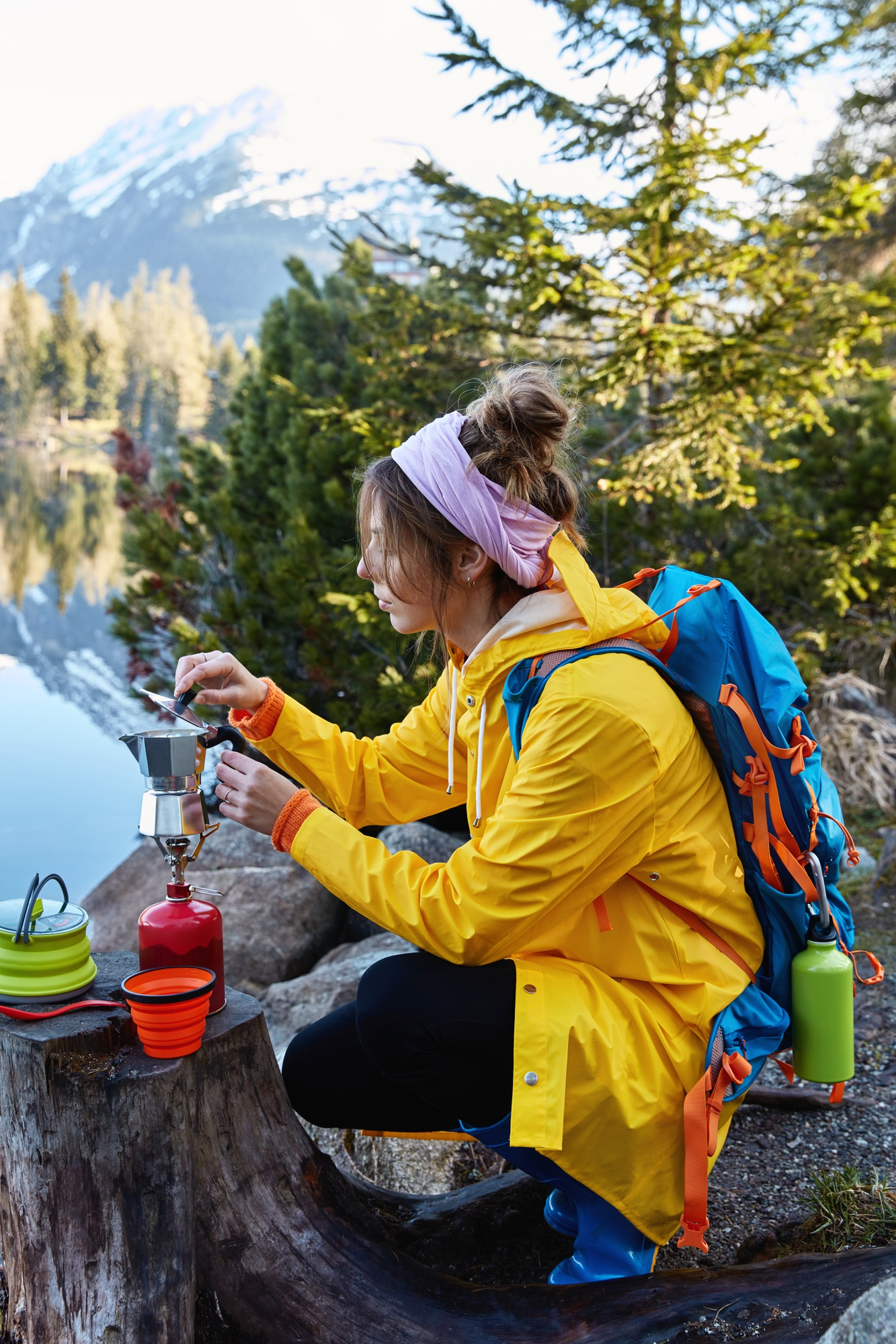 Femme en randonnée utilisant du matériels de camping pour préparer un café en pleine nature
